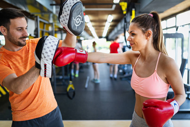 Happy fit woman exercise boxing with personal trainer at the gym. Sport, health, people concept - Fotoğraf, Görsel