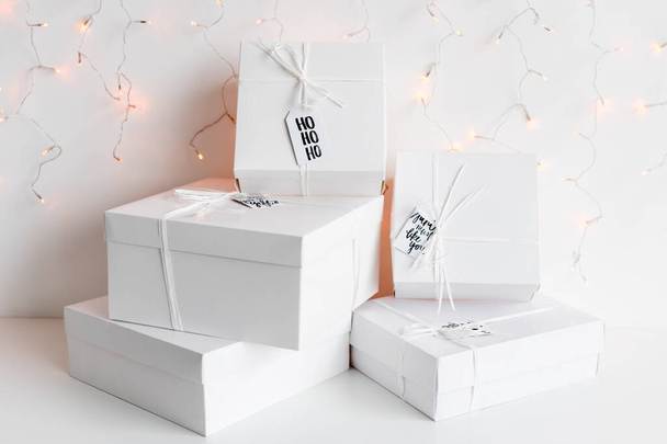 Yeni yıl hediyeleri, arka planda beyaz kutular ve kış tatili süslemeleri. Hediye kutularıyla Noel arkaplanı. Noel kutlaması için hediyeler - Fotoğraf, Görsel