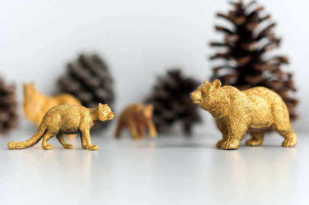 黄金のクリスマスの装飾、マーテンとクマのフィギュア、モデルのおもちゃ。背景に松ぼっくり。クリスマスのコンセプト - 写真・画像