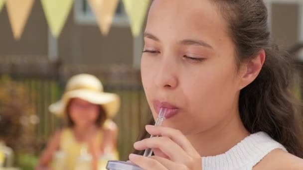 Retrato de cerca de la hermosa mujer de raza mixta bebiendo limonada en el caluroso día de verano sonriendo a la cámara - Imágenes, Vídeo