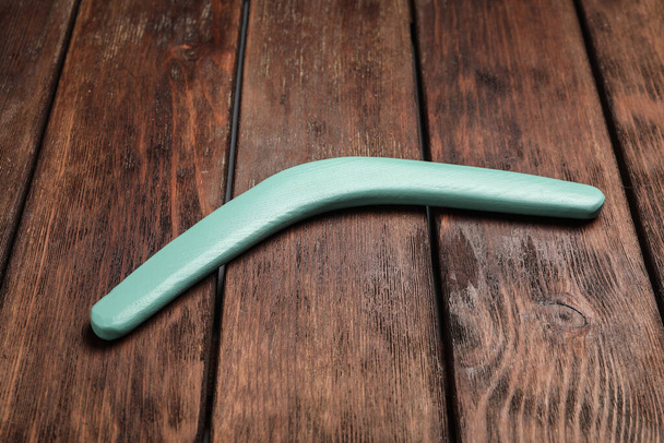 Turquoise boomerang on wooden background. Outdoors activity - Fotó, kép