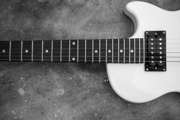 Piękny vintage biały kształt gitary elektrycznej na szarym tle w czerni i bieli - Zdjęcie, obraz