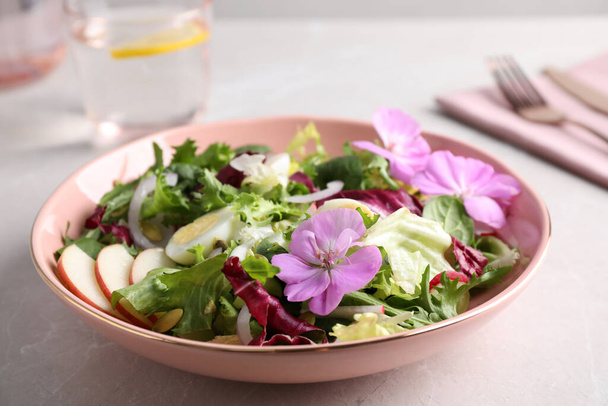 Fresh spring salad with flowers on grey table, closeup - Photo, Image