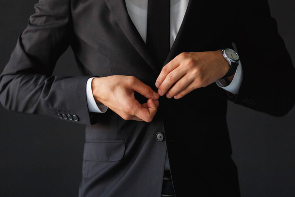 The groom fastens the button of his black jacket - Valokuva, kuva