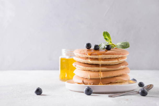 Sweet homemade stack of pancakes with honey, fresh blueberry on white background. Space for text. Close up - Foto, Bild