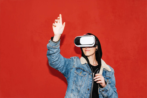 Nuori tyttö käyttää VR lasit edessä punainen tausta. Virtuaalitodellisuuslaitetta käyttävä henkilö. - Valokuva, kuva