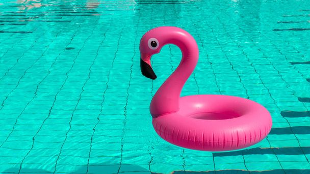 Strandflamingo. Roze opblaasbare flamingo in zwembadwater voor zomerse strand achtergrond. Trendy zomerconcept - Foto, afbeelding
