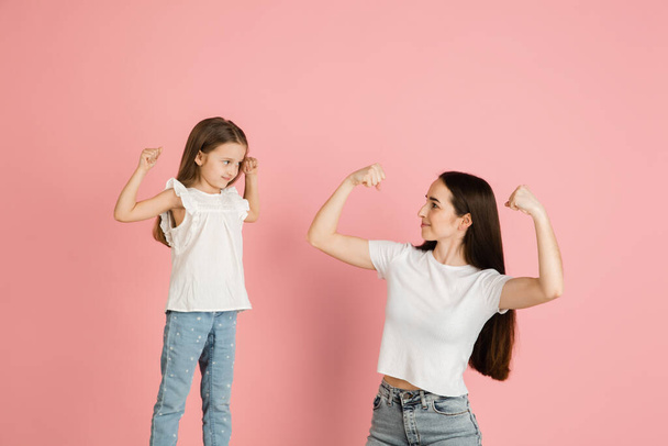 Young woman and girl, mother and daughter isolated over pink background. - Photo, Image