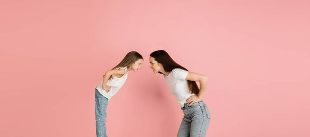 Two people, mother and daughter posing isolated over pink background. - Фото, зображення