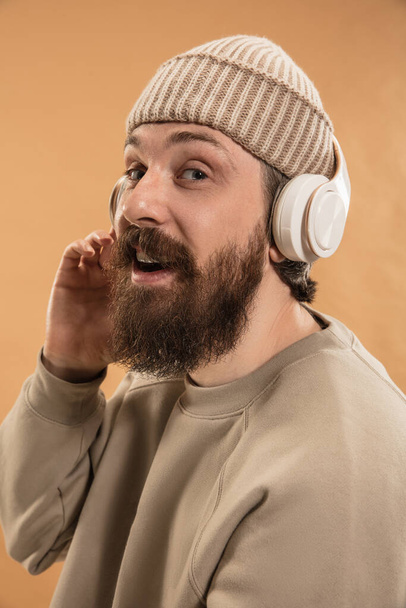 Portrait of Caucasian man in headphones and hat isolated on light background. - Φωτογραφία, εικόνα