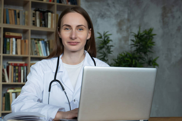 Woman doctor using on her laptop computer in medical office - Foto, afbeelding