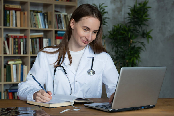 Woman doctor using on her laptop computer in medical office - Foto, imagen