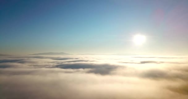 Foto aérea de majestuoso amanecer en las montañas. Valle entre las montañas está cubierto de niebla y está iluminado por los cálidos rayos del sol naciente. Montañas cubiertas de bosque natural. - Metraje, vídeo
