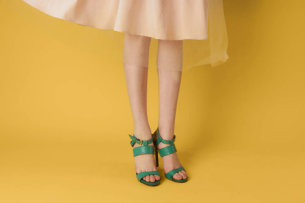 Fashionable shoes green shoes female feet shopping yellow background - Foto, imagen