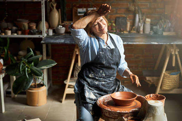 Χαρούμενη ηλικιωμένη γυναίκα που φτιάχνει κεραμικά στο εργαστήριο - Φωτογραφία, εικόνα