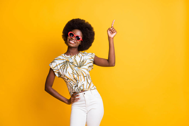 Photo of pretty cute lady stand point empty space dress spectacles t-shirt trousers isolated on yellow color background - 写真・画像
