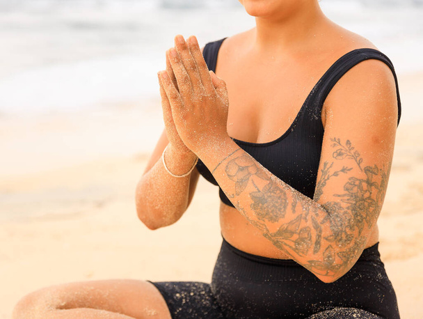Закройте мудру намасте. Йога на пляже. Женщина, сидящая на песке и практикующая йогу с мудрой намасте. Медитация и концентрация. Концепция йоги. Пляж Томас, Бали, Индонезия - Фото, изображение