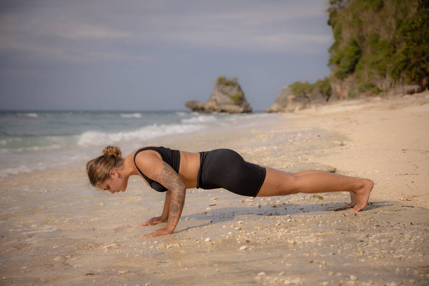 Yoga houding. Blanke vrouw die Phalakasana beoefent, Plank Pose. Sterk lichaam. Een gezonde levensstijl. Zelfzorgconcept. Yoga retraite. Thomas strand, Bali, Indonesië - Foto, afbeelding