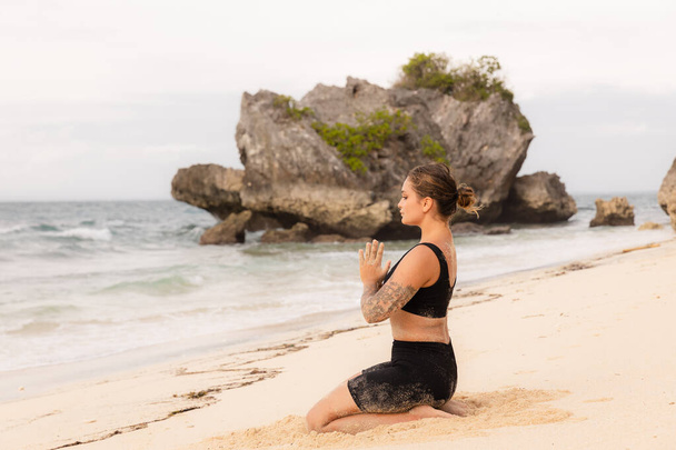 Elmas Poz, Vajrasana yoga pozu. Kumsalda yoga yapan beyaz bir kadın. Eller namaste mudra 'da. Vücuda uygun. Kişisel bakım konsepti. Yoga inzivası. Thomas Sahili, Bali, Endonezya - Fotoğraf, Görsel