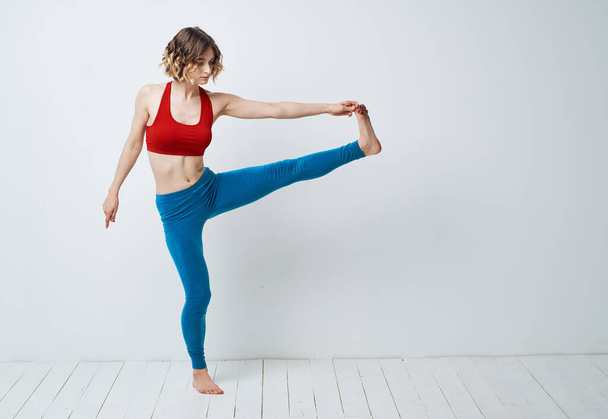 vrouw in blauw leggings doet sport op een lichte vloer binnen in volle groei - Foto, afbeelding