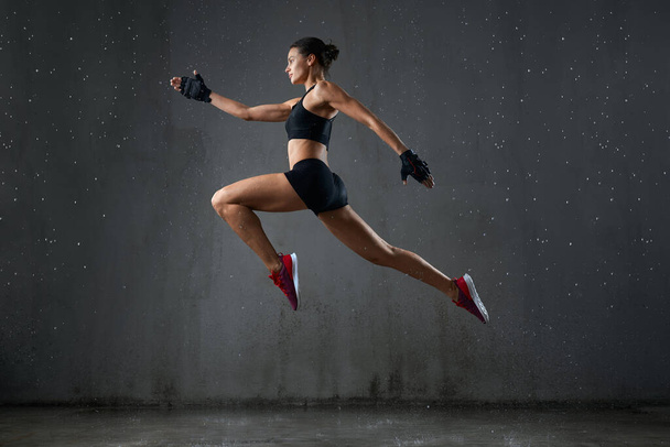 Strong wet woman posing during jump. - Fotografie, Obrázek