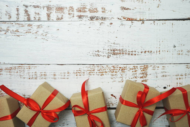 Gift boxes with red ribbon on wooden background - Фото, изображение