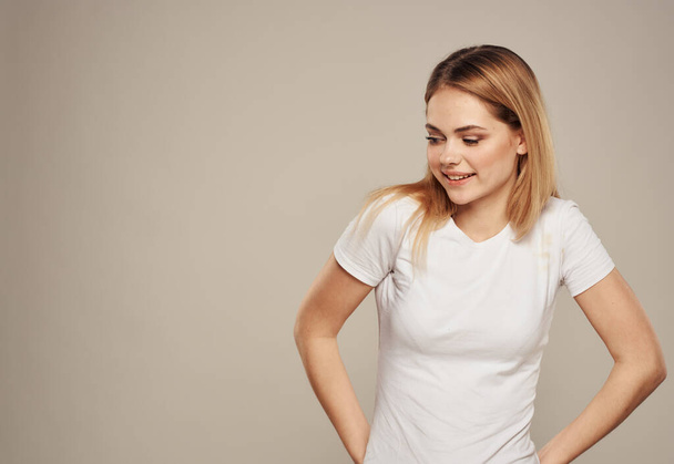 Belle femme dans un T-shirt blanc sur un fond gris gestes Espace de copie - Photo, image
