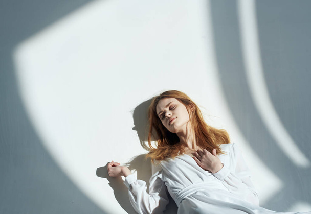woman with red hair leaning against the north wall and a falling shadow Indoors - Foto, immagini