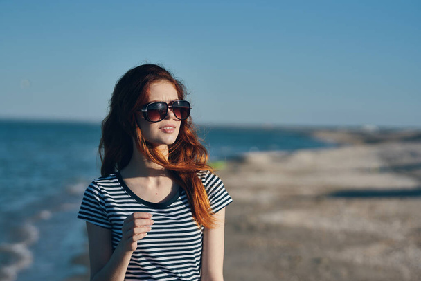 portret pięknego podróżnika z okularami czerwonymi włosami t-shirt plaża letni krajobraz morze - Zdjęcie, obraz