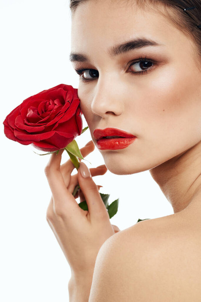 Mujer romántica con flor roja fragante cerca de la cara piel limpia cosmetología dermatología - Foto, imagen