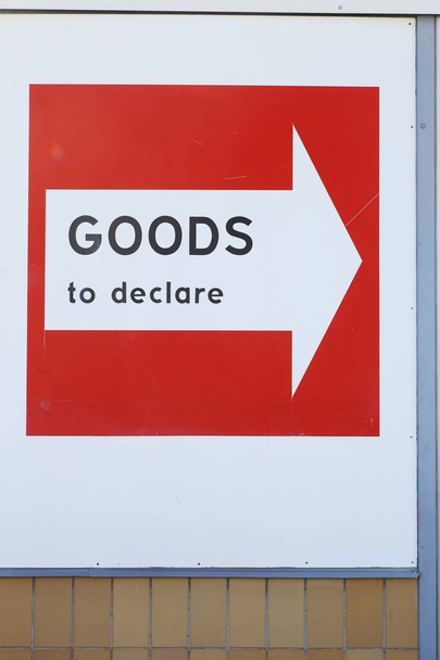 Σήμανση με βέλος σε κόκκινη πινακίδα για όσους έχουν εμπορεύματα να δηλώσουν στο τελωνείο. - Φωτογραφία, εικόνα
