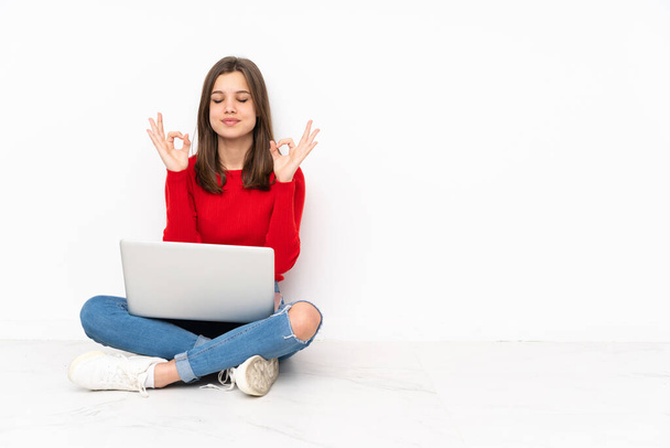 Tenaager Mädchen arbeitet mit PC isoliert auf weißem Hintergrund in Zen-Pose - Foto, Bild