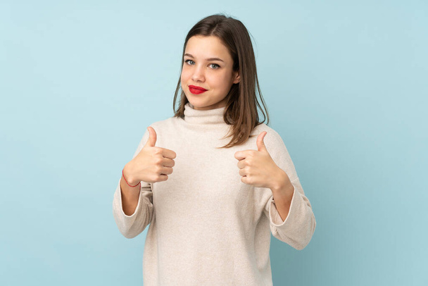Teenager girl isolated on blue background giving a thumbs up gesture - Valokuva, kuva