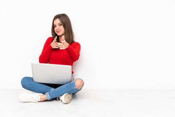 Tenaager Mädchen arbeitet mit PC isoliert auf weißem Hintergrund zeigt nach vorne und lächelt - Foto, Bild