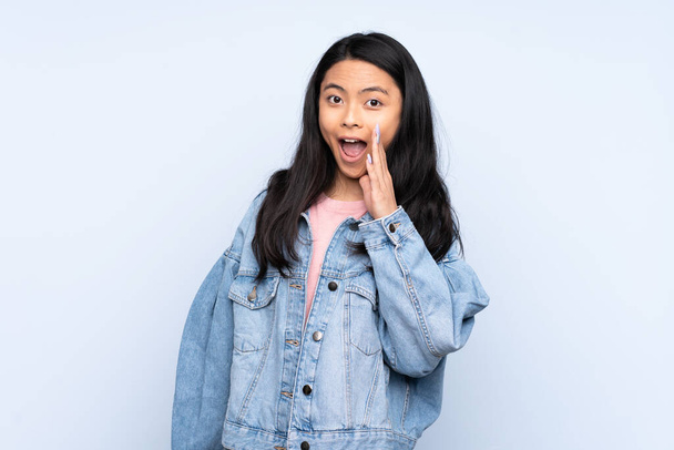 Teenager Chinese woman isolated on blue background with surprise and shocked facial expression - Fotoğraf, Görsel