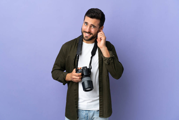 Fotografo uomo su sfondo viola isolato frustrato e coprendo le orecchie - Foto, immagini