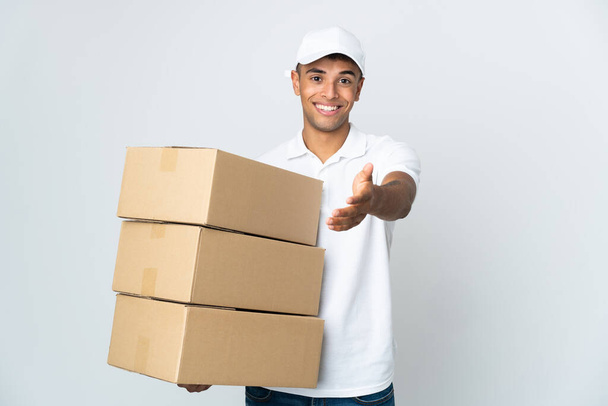 Delivery Brazilian man isolated on white background shaking hands for closing a good deal - Photo, Image
