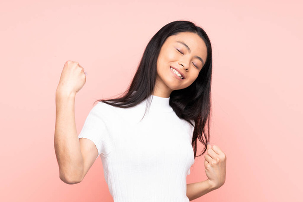 Teenager Chinese woman isolated on pink background celebrating a victory - Photo, Image