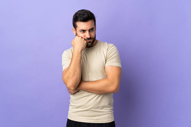 Young handsome man with beard over isolated background with tired and bored expression - Photo, Image