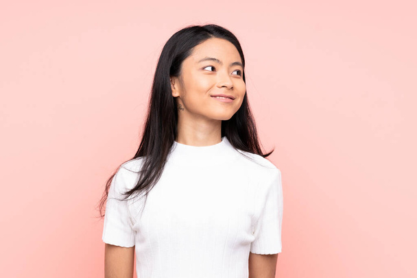 Teenager Chinese woman isolated on pink background looking side - Foto, Bild