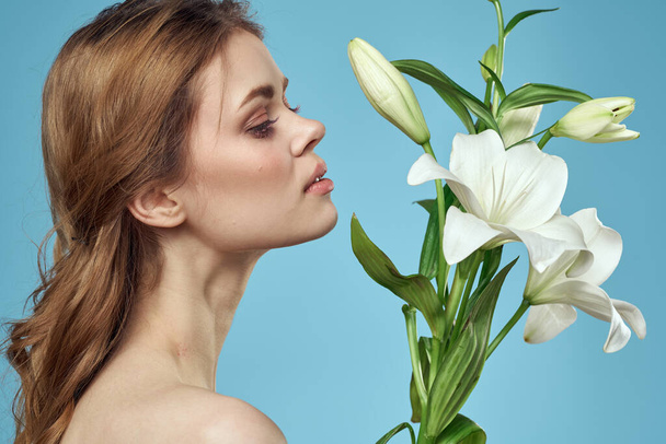 Όμορφη γυναίκα γυμνοί ώμοι λουλούδια διακόσμηση καθαρό δέρμα μπλε φόντο - Φωτογραφία, εικόνα