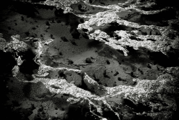Zwart-wit beeld van een plas met natuurlijk patroon op wateroppervlak. - Foto, afbeelding