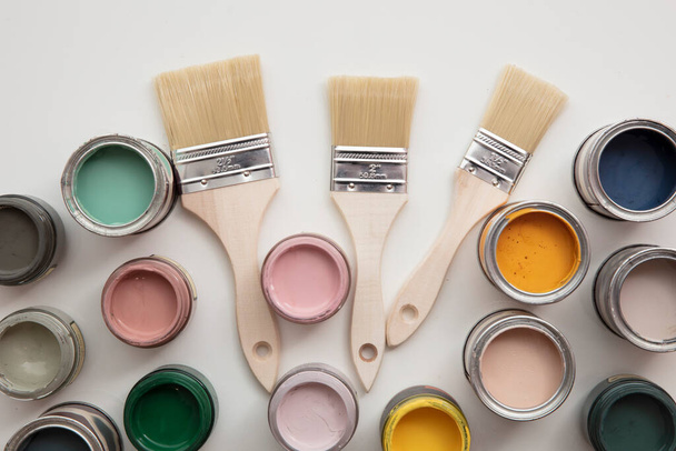 Overhead view of a DIY paint brush with colorful sample paint pots - Fotoğraf, Görsel