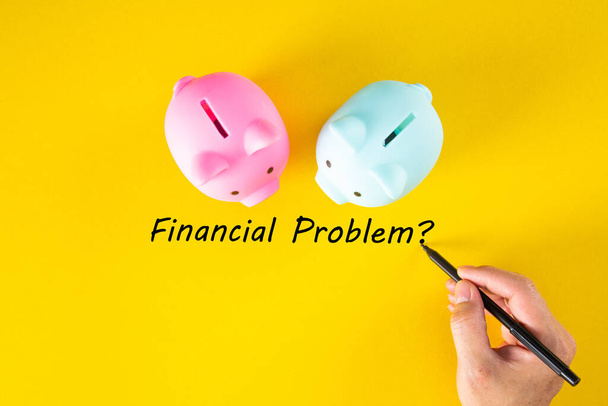 A hand writes the words FINANCIAL PROBLEM on the yellow background. Business and finance concept - Photo, Image