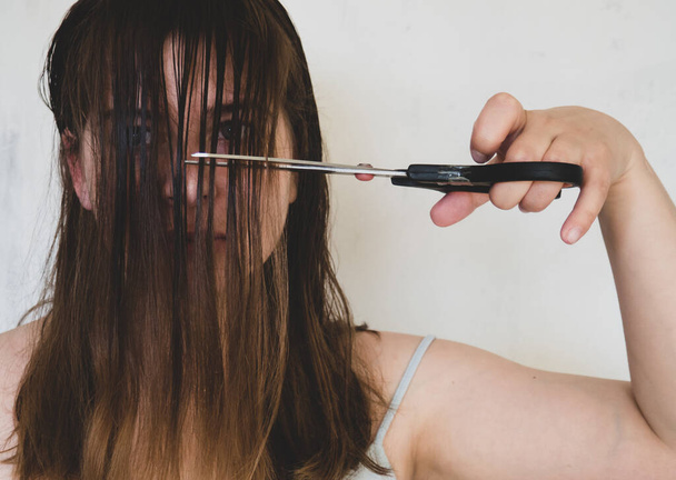 joven chica corta su cabello con tijeras - Foto, Imagen