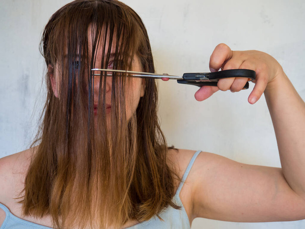 joven chica corta su cabello con tijeras - Foto, Imagen
