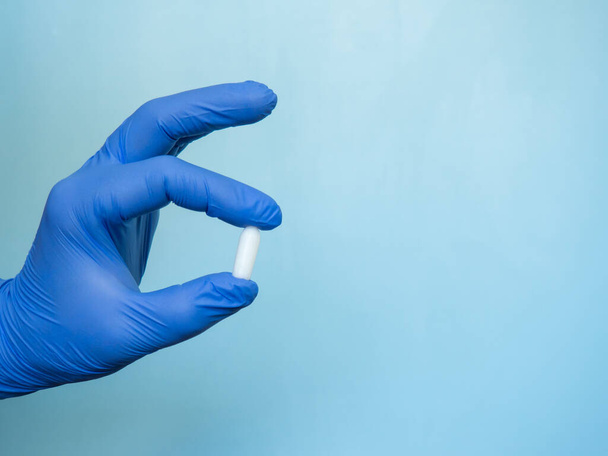 świeca odbytnicy jest trzymana za rękę w niebieskiej rękawicy medycznej - Zdjęcie, obraz