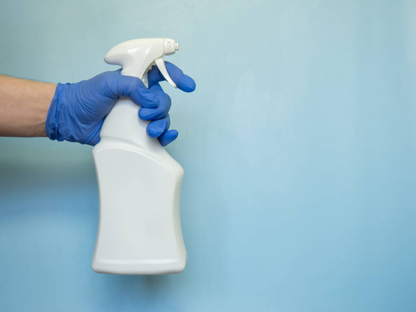 Käsi kumihanskassa pitää pulloa antiseptistä suihketta. Suojelun käsite - Valokuva, kuva