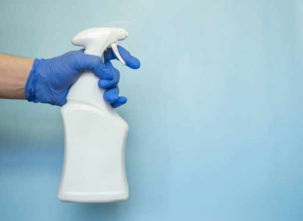 A hand in rubber glove hold the bottle of antiseptic spray. Protection concept - Photo, Image