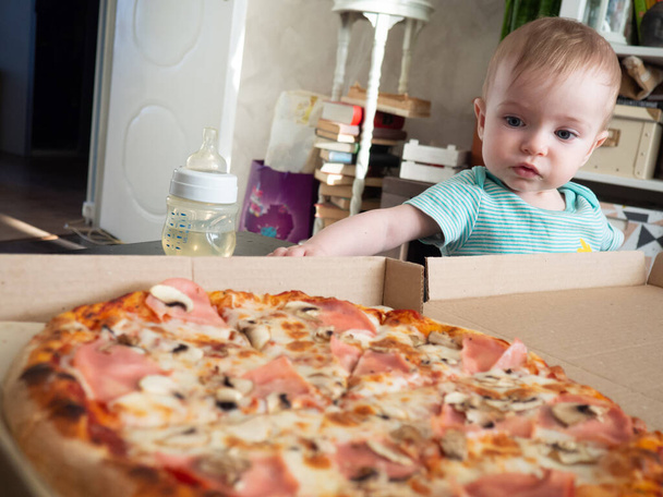 Küçük bir çocuk bir dilim pizzaya uzanır. - Fotoğraf, Görsel